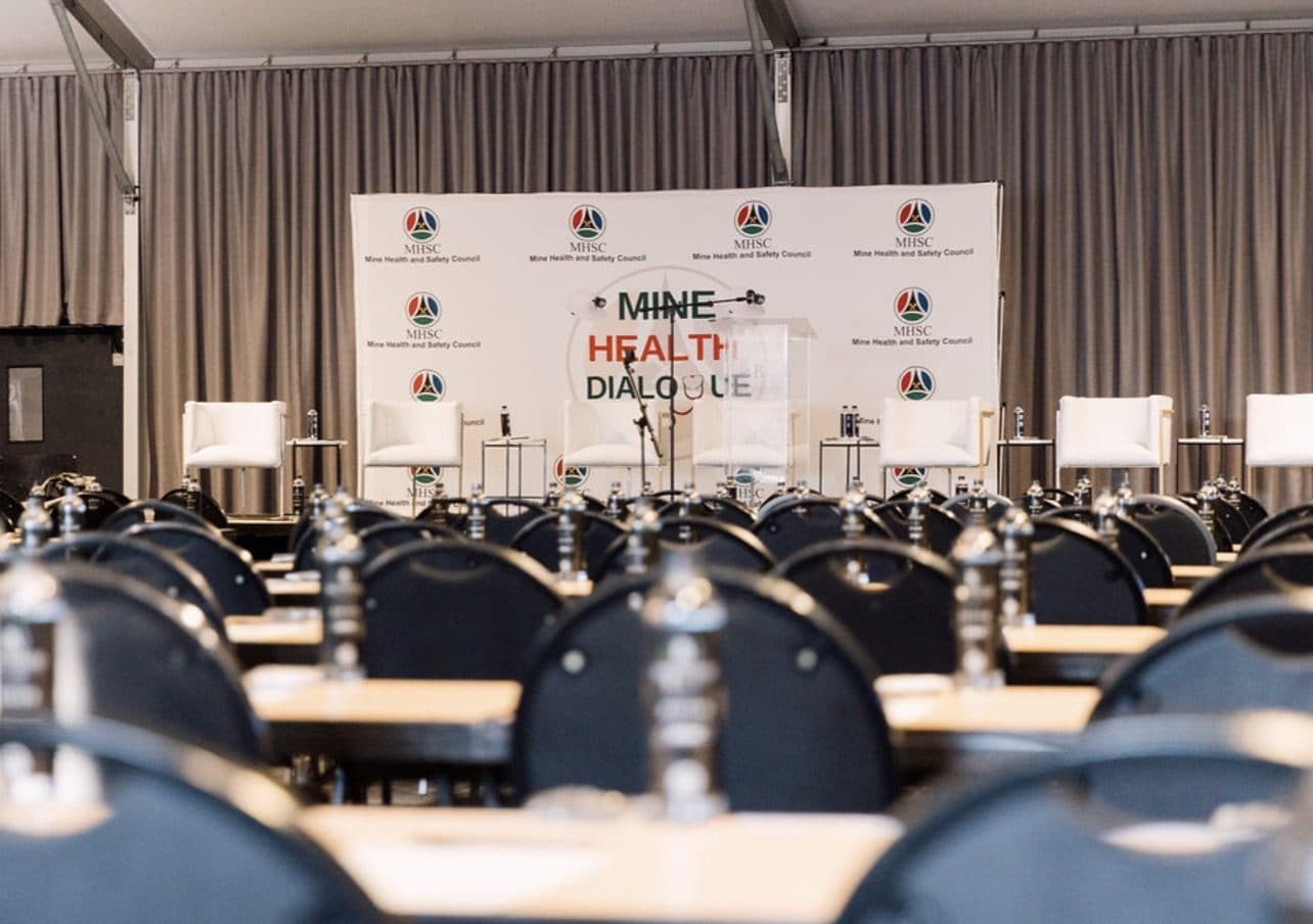 Conference stage with white panel chairs set for the Mine Health Dialogue